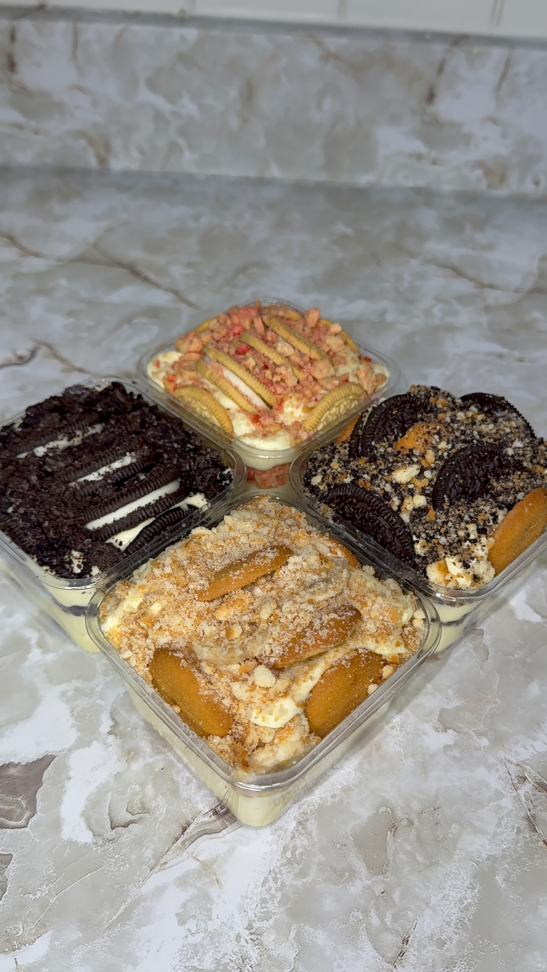 Four Not Nanas pudding pans on a marble countertop — Banana Bliss, Oreo Craze, Blondie and Strawberry Crunch